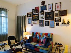 The art-filled wall collage compliments the patchwork our Minnelli Loveseat from Urban Ladder and we are absolutely loving how Wegner Shell Chair and Capella Side Tables makes it extra chic!